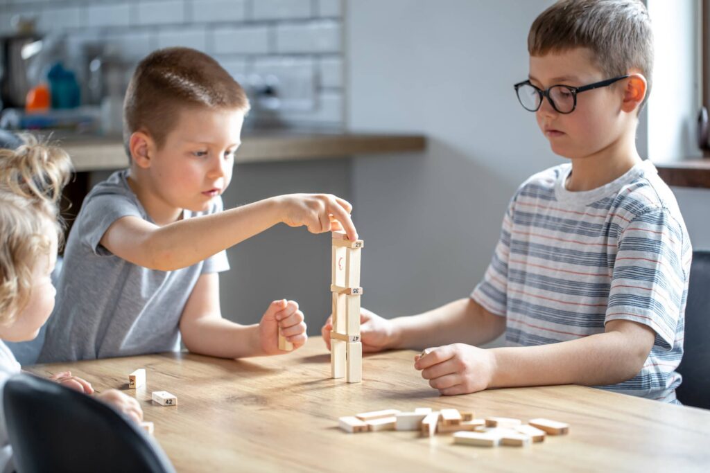 Children play a board game with a wooden turret at home.